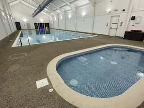 Una piscina interior con carriles delimitados y una zona separada para hidromasaje.