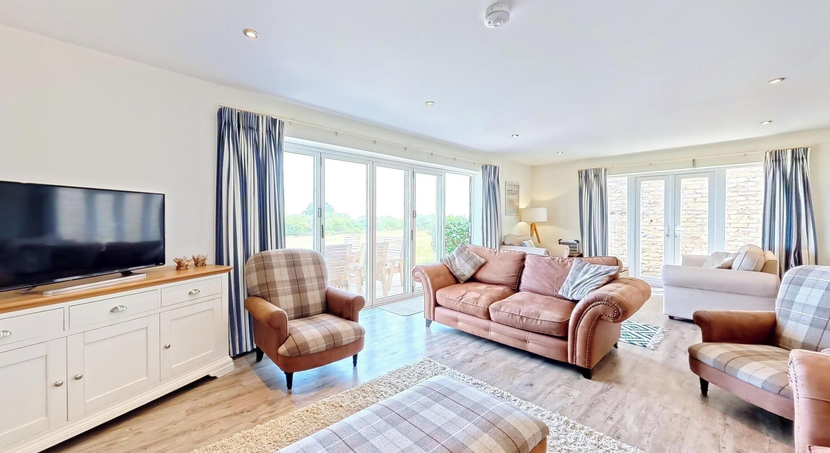 A spacious living room with a flat-screen TV, a sofa, a chair, and a coffee table.