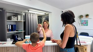 A reception desk with a counter, a computer, and a shelf with binders. - ZEcamping 3 étoiles pet friendly locatif TV 24m2 4 pers (Hyères)