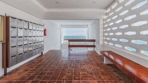 A hallway with metal mailboxes, a wooden bench, and a window with a view. - Apartment 'Oásis' with Sea View, Wi-Fi and Air Conditioning (Sesimbra)
