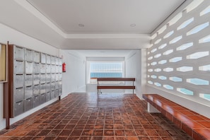 A hallway with metal mailboxes, a wooden bench, and a window with a view.