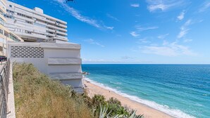 A coastal building with balconies overlooking the sea, a clear sky, and a bird in flight. - Apartment 'Oásis' with Sea View, Wi-Fi and Air Conditioning (Sesimbra)
