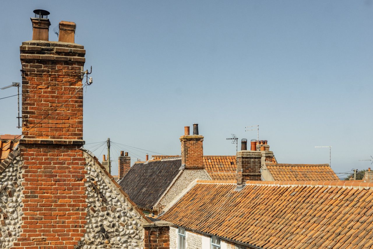 Une rangée de maisons traditionnelles en briques, avec des toits en tuiles et des cheminées.