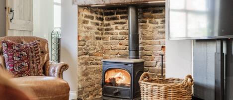 A cozy room with a stone fireplace, a leather armchair, and a modern refrigerator.