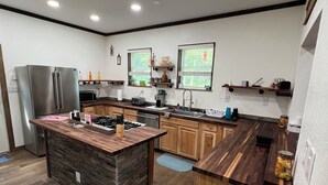 A modern kitchen with a central island, wooden cabinets, and built-in appliances. - Charming 3-BR Cabin/House, Pool, creek, 35Acres with Fiber Internet in Pikeville (Pikeville)