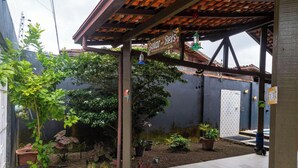 A covered outdoor area with a sign reading "Solar dos Reis," surrounded by potted plants and a small garden. - Casa na Ilha com Churrasqueira (Mosqueiro)