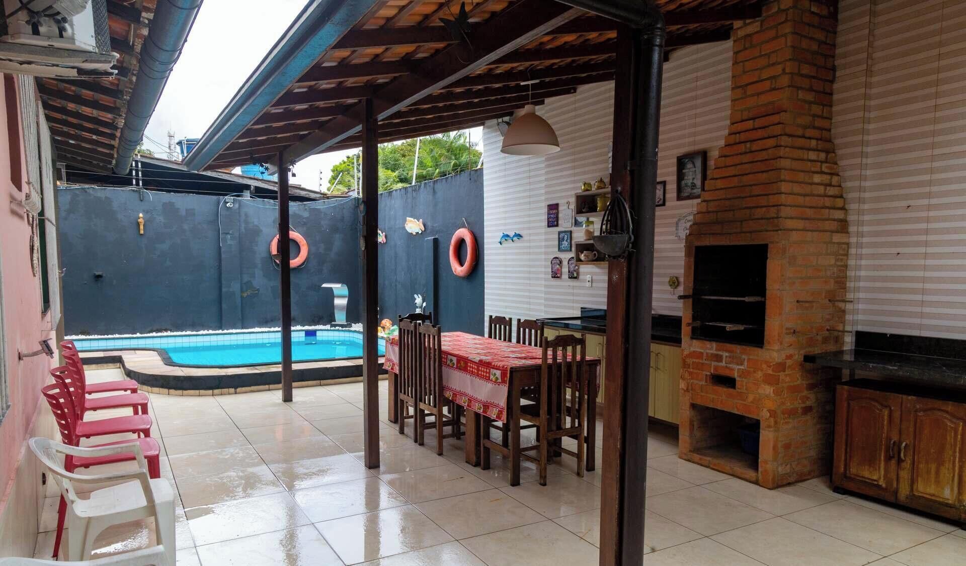 Un patio exterior con piscina, zona de barbacoa y comedor.
