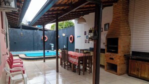 An outdoor patio with a pool, a barbecue area, and a dining setup. - Casa na Ilha com Churrasqueira (Mosqueiro)