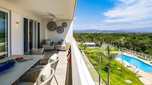 En balkon med pool, udendørs siddepladser og udsigt over landskabet.