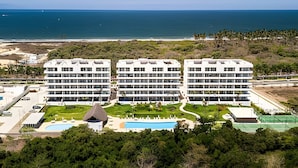 Et moderne hotel med flere etager, en swimmingpool og havudsigt.