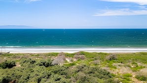 Kystlandskab med strand, hav og fjerne bjerge.