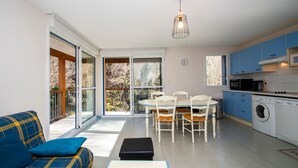 Una cuina moderna amb zona de menjador, sofà i rentadora.