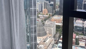 A high-rise building with a view of a cityscape through a window with white curtains.