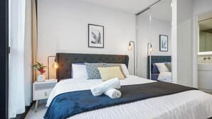 A bedroom with a bed, bedside tables, a mirror, and wall art.