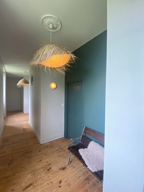 Un couloir doté d’un plancher en bois, d’un banc et de deux lampes suspendues.