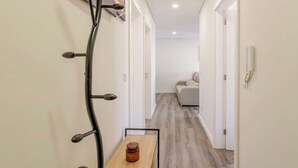 A hallway with a wooden table, a wall-mounted light fixture, and a sofa in the background.