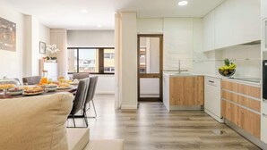A modern kitchen with white cabinets, a wooden countertop, and a dining area with a table set for breakfast.