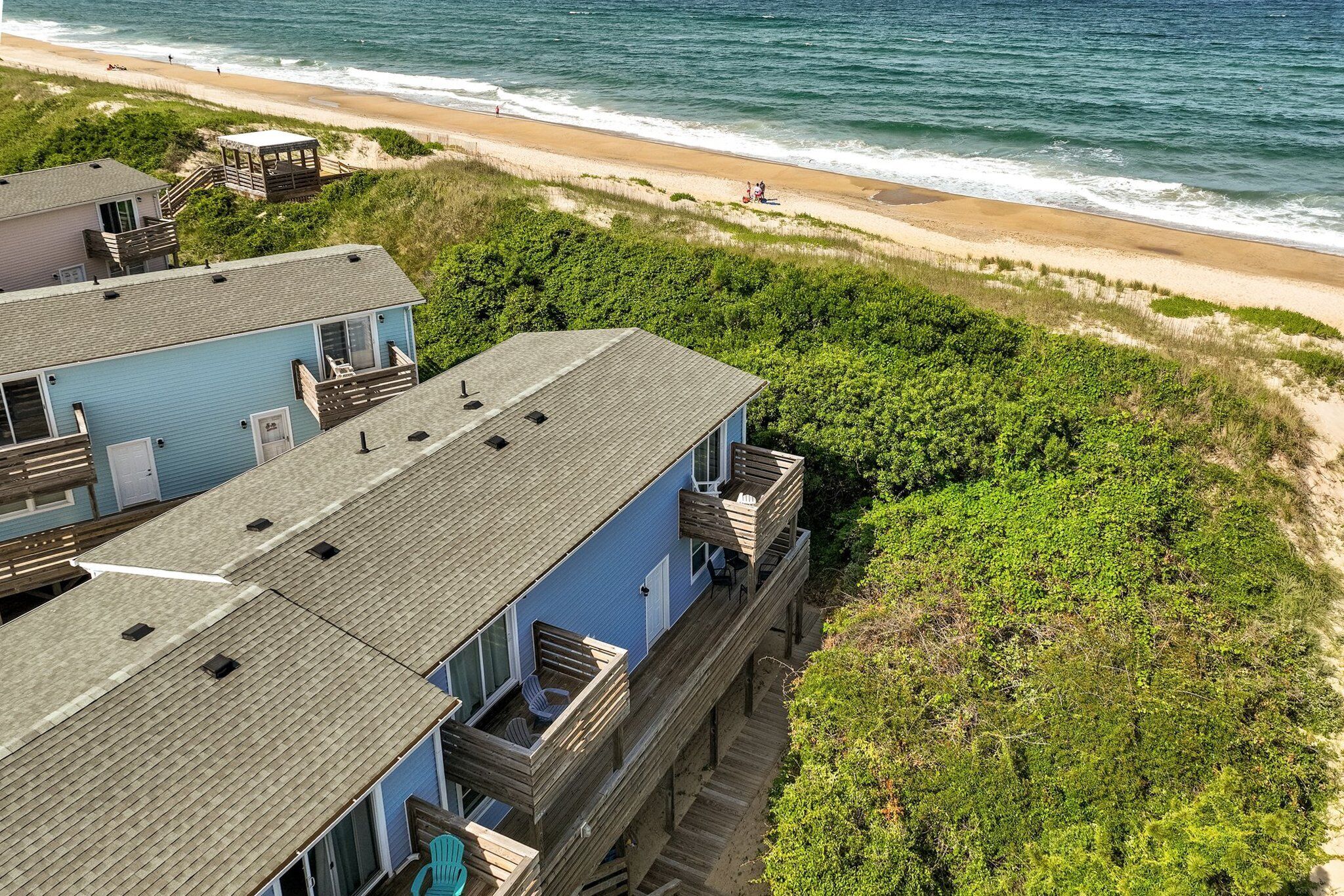 A beachfront property with a two-story building, wooden balconies, and a beach view.