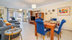 Un salon moderne avec un canapé, une table basse et un coin repas comprenant une table en bois et des chaises bleues.