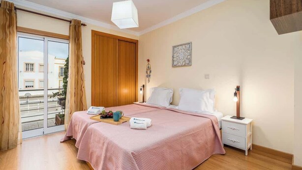 Une chambre d’hôtel avec un lit, une table de chevet et une vue sur l’extérieur, accessible par une porte coulissante.