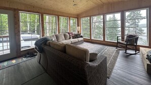 A cozy room with a large window, a ceiling fan, and a wicker sofa. - Comfort and Convenience. Family and pet friendly. Close to the action! (International Falls)