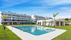 A modern hotel with a rectangular pool, a covered outdoor area, and a multi-story building with balconies. - Lujo Apartments Estepona (Estepona)