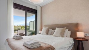 A hotel room with a large bed, a bedside table with a lamp, and a view of the outdoors through a sliding door. - Lujo Apartments Estepona (Estepona)