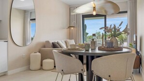 A modern dining area with a round table, chairs, and a large mirror on the wall. - Lujo Apartments Estepona (Estepona)