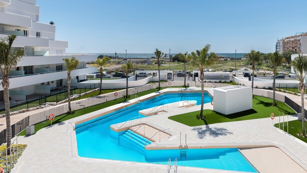 Ein moderner Poolbereich mit freiem Blick auf das Meer, umgeben von weißen Gebäuden und Palmen.