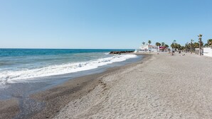 Ein Strand mit einem Gebäude, Palmen und blauem Himmel.