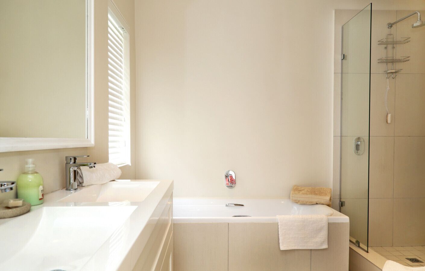 Une salle de bain avec deux lavabos, une douche et un espace douche séparé par des parois en verre.