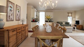 A spacious living area with a wooden dining table, a sofa, and a TV.
