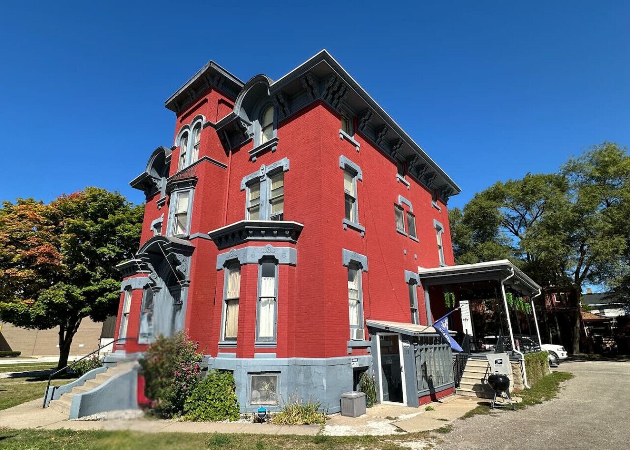 A red brick building with a corner entrance and a covered porch.