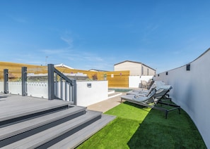 A rooftop patio with a pool, outdoor seating, and a staircase leading to an upper level.