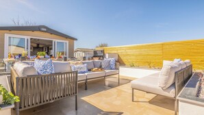 A patio with outdoor furniture, a barbecue grill, and a yellow wall.