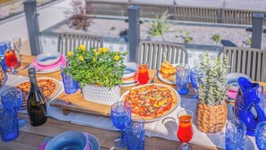 An outdoor dining area with a wooden table set for a meal, surrounded by chairs and a sofa.