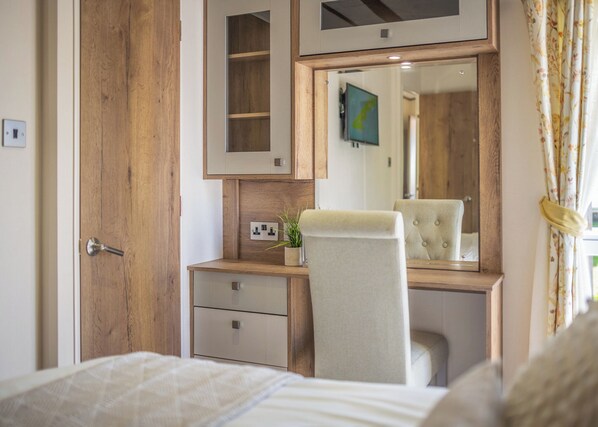 Ein Schlafzimmer mit einem Holzschrank, einem Nachttisch mit Spiegel, einem Sessel und einem Bett.