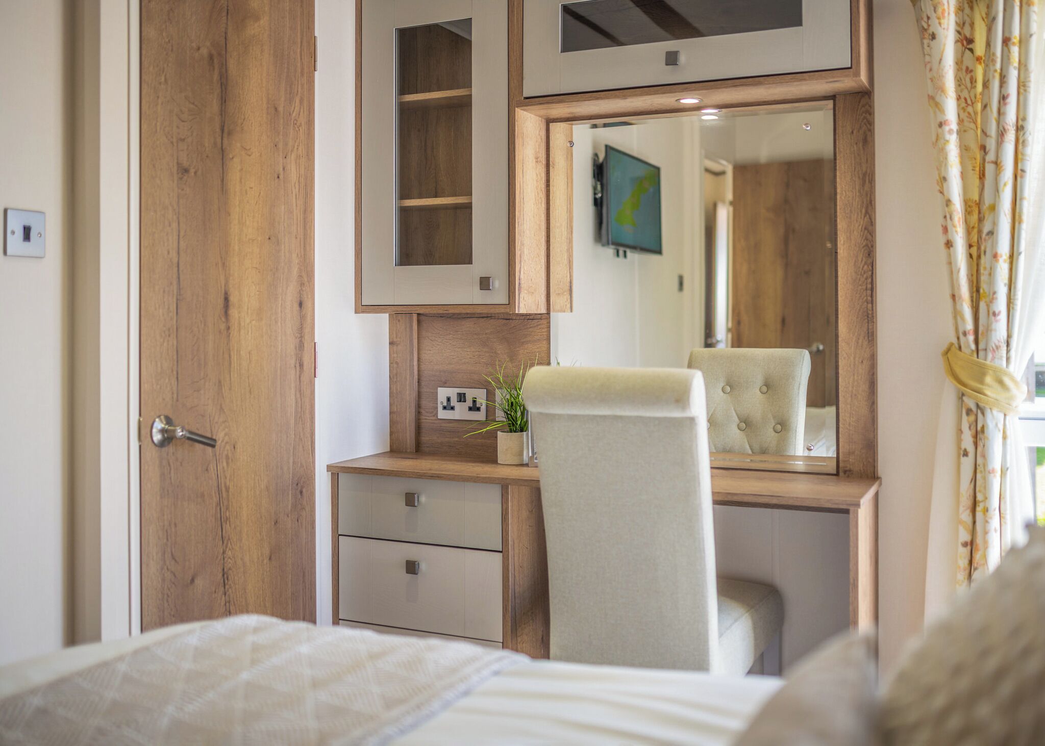 Une chambre à coucher avec une armoire en bois, une table de chevet avec un miroir, une chaise et un lit.