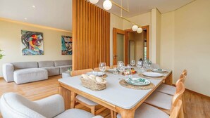 A modern dining area with a wooden table set for four, surrounded by cushioned chairs. - Deluxe House | Terrace & BBC by HostWise (Parchal)