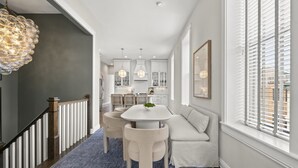 A modern kitchen with white cabinets, pendant lights, and a dining area with a round table and chairs.