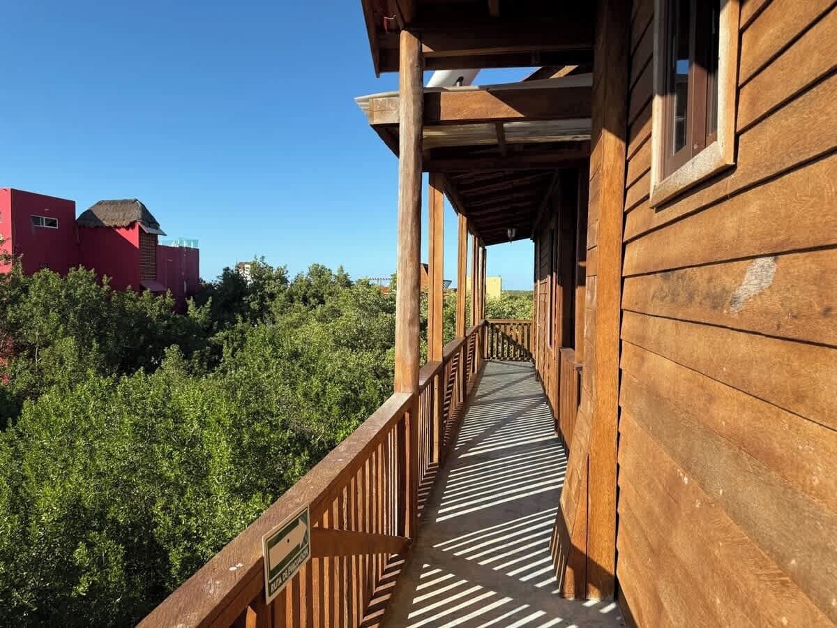 Un pontile in legno con ringhiera che conduce a un edificio con tetto di paglia.