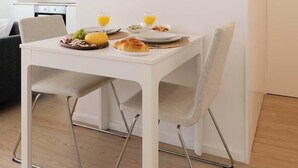 Ein stilvoller Essbereich mit einem weißen Tisch, zwei Stühlen und einem Gemälde an der Wand.