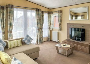 Una sala de estar con sofá, mesa de centro, televisor y cortinas.