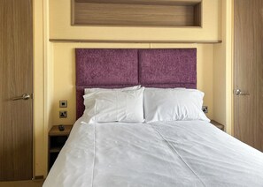 Een hotelkamer met een bed, een houten hoofdeinde en een nachtkastje met een afstandsbediening.