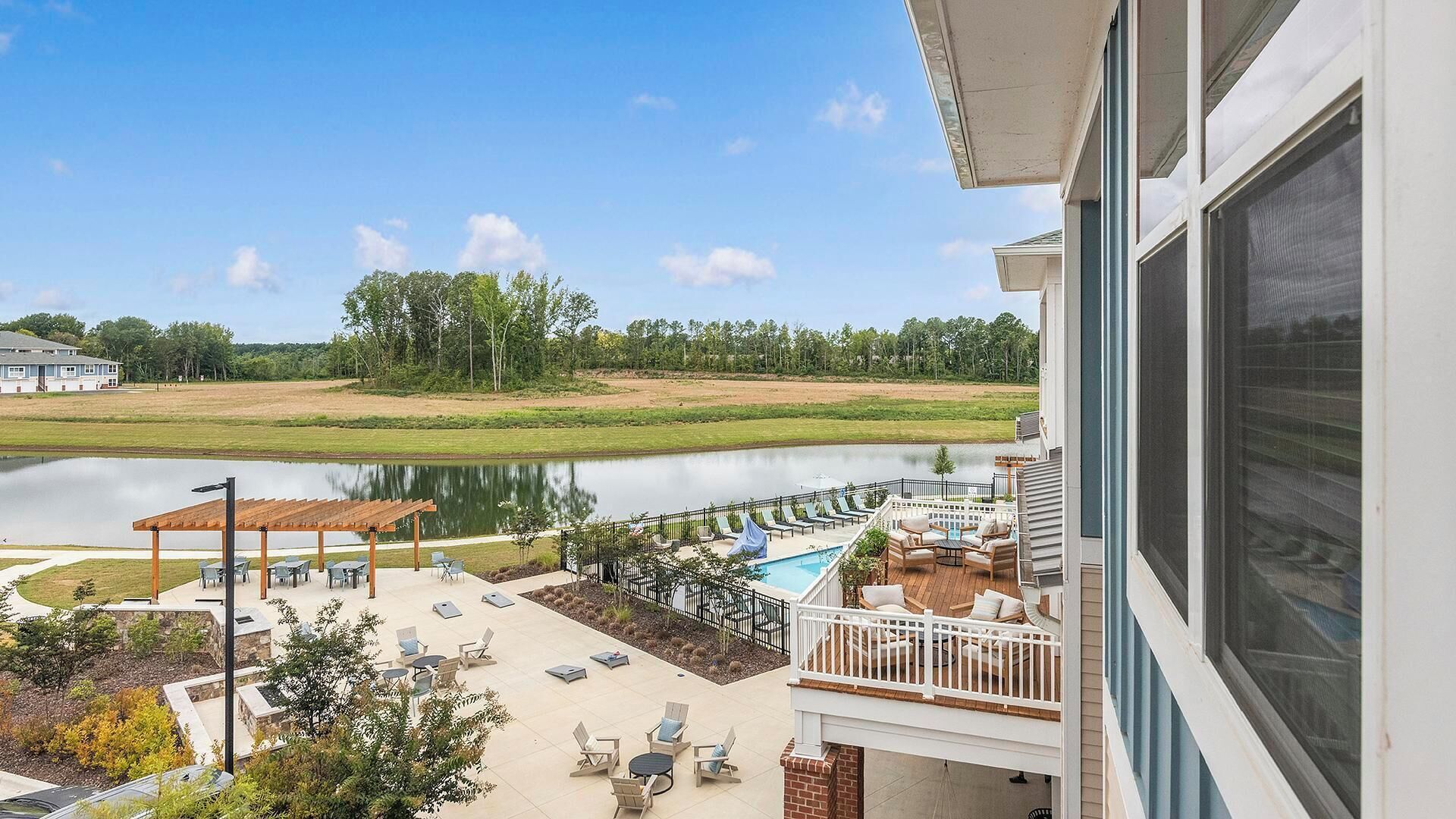 A view of a lakeside property with a pool, outdoor seating, and a gazebo.