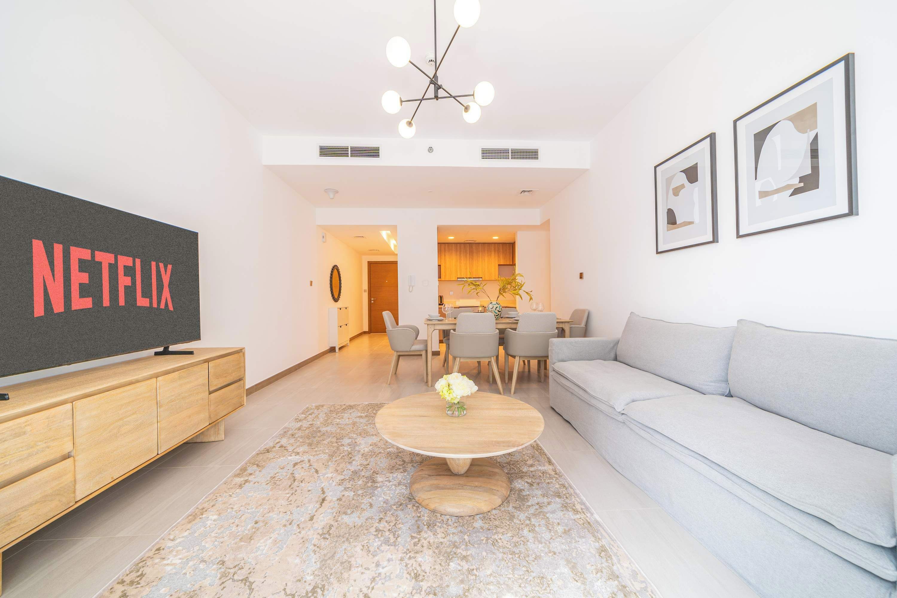 Una sala de estar moderna con un televisor de pantalla plana, un sofá gris, una mesa de centro de madera y arte abstracto en la pared.