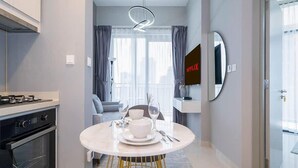 A modern kitchen with a dining area, a built-in oven, and a dining table set for two. - Spacious & Fully Furnished 1BR in Zada (Dubai)