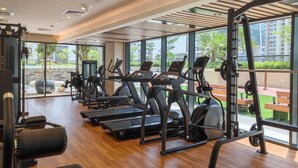A gym with treadmills, elliptical machines, and weightlifting equipment. - Spacious & Fully Furnished 1BR in Zada (Dubai)