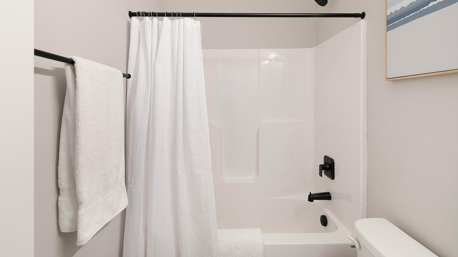 A modern bathroom with a glass-enclosed shower, a white toilet, and a towel hanging on a rack.