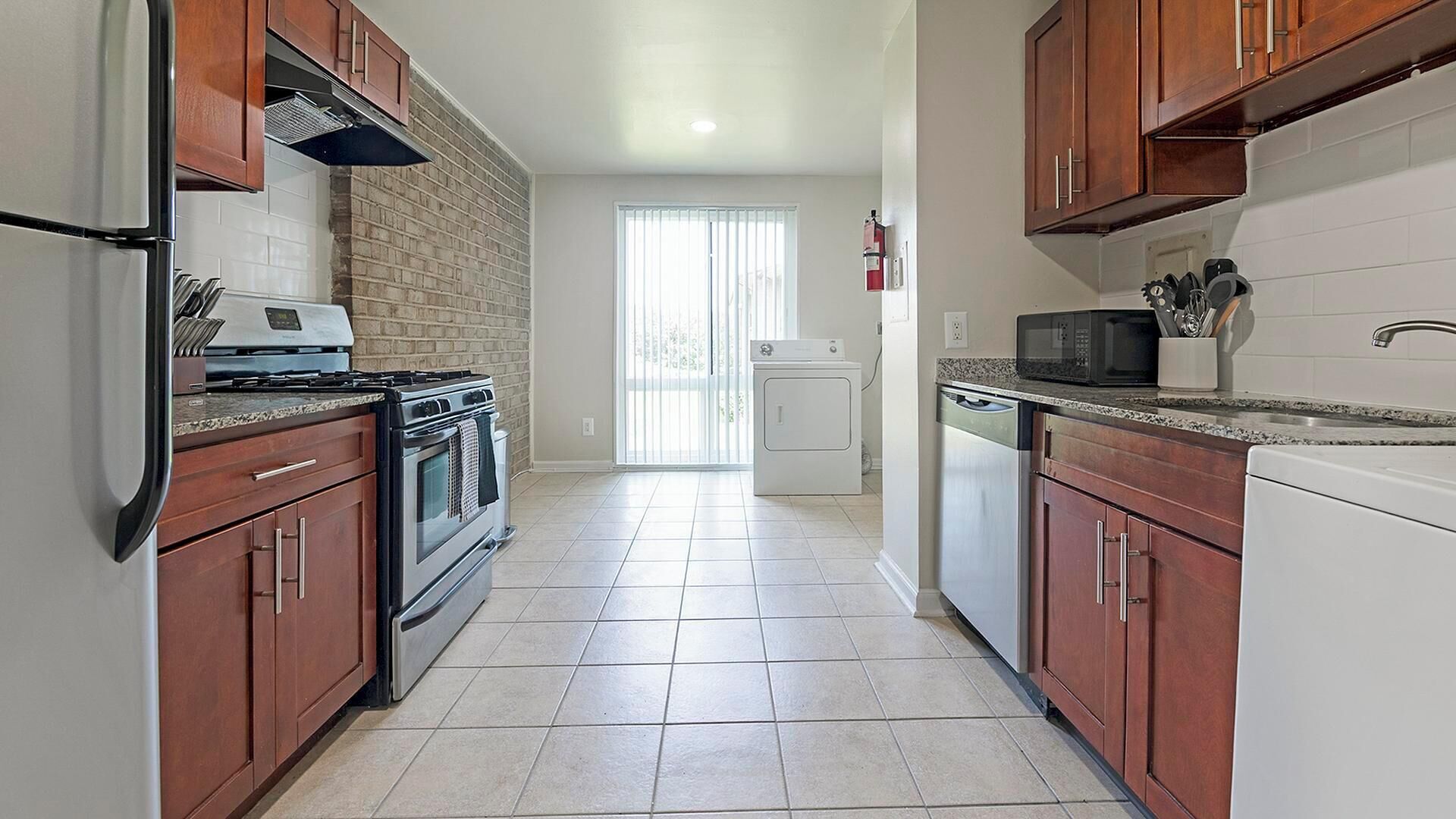 A kitchen with wooden cabinets, a stainless steel refrigerator, a microwave, a stove, and a dishwasher.